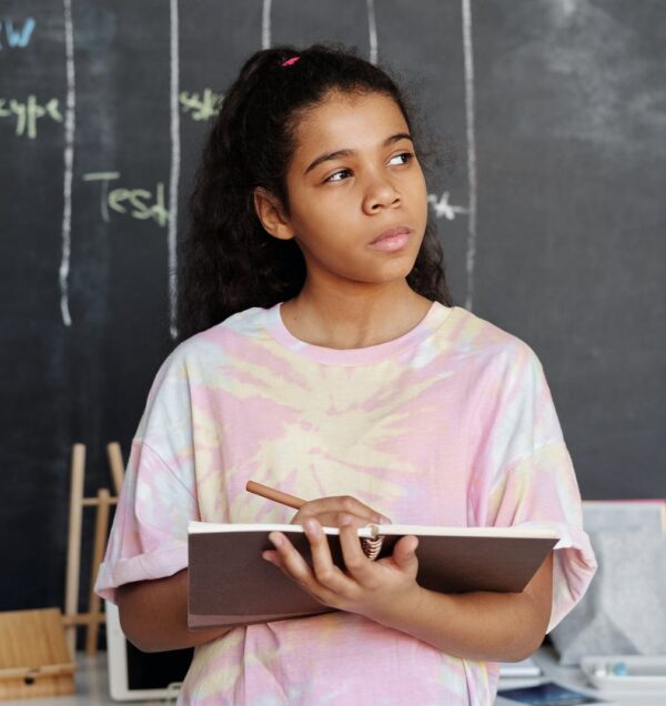 woman in pink and yellow crew neck t shirt holding brown notebook